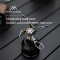 Miniature silver gas stove with an orange flame, on a dark background, showcasing its compact size