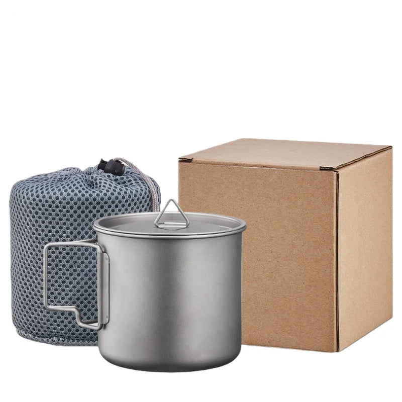 Titanium camping mug with a folding handle, shown in an outdoor setting (view 6)