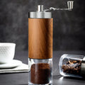 Portable stainless steel hand-crank coffee grinder with a wood grain finish