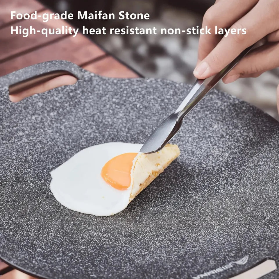 34cm round black aluminum alloy grill pan with a ridged cooking surface, shown on a camp stovetop (view 2)