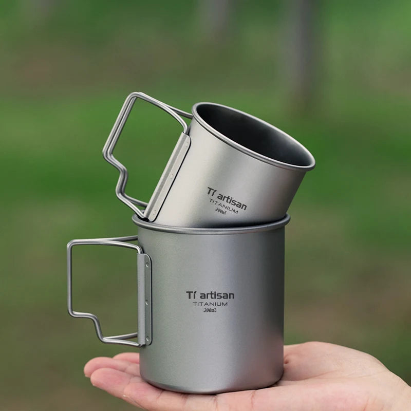 Titanium camp coffee cup with a folding handle, shown in various sizes with a mesh storage bag. (view 3)