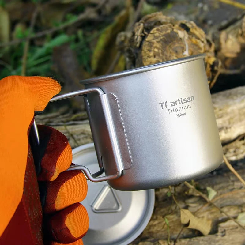 Titanium camp coffee cup with a folding handle, shown in various sizes with a mesh storage bag. (view 2)