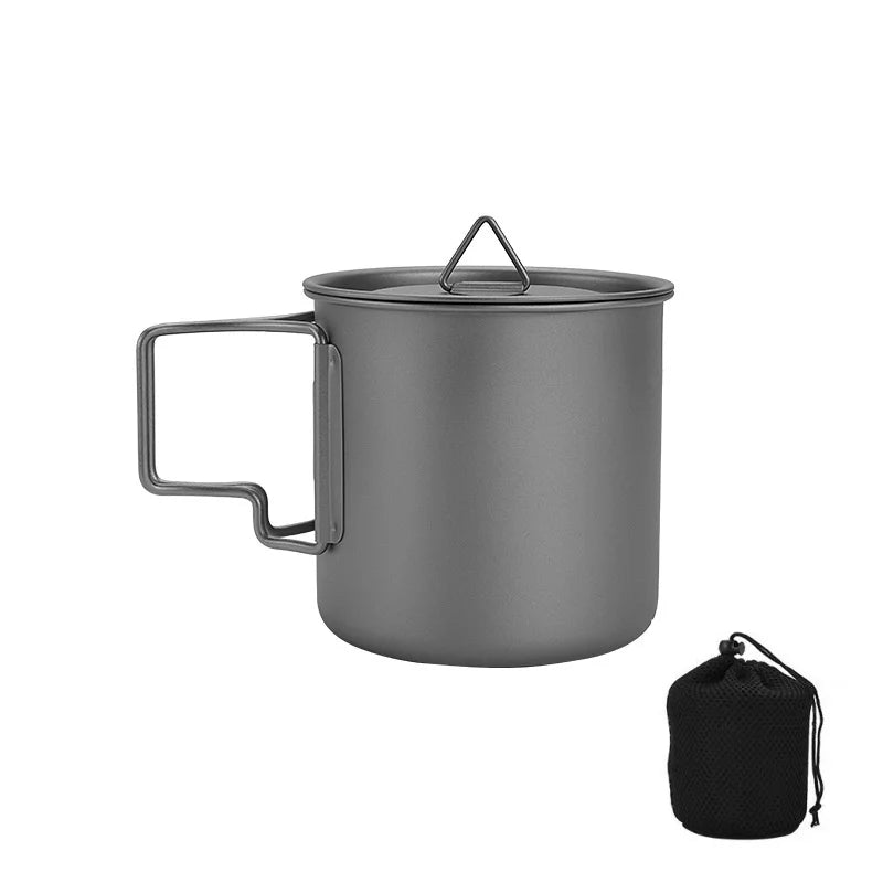 Titanium camping mug with a folding handle, shown in an outdoor setting (view 7)